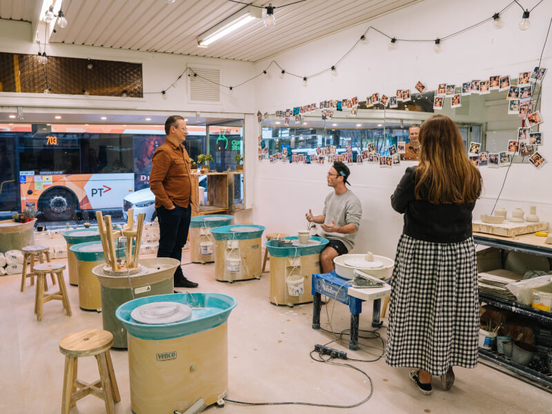 Three people stood around in a pottery studio.